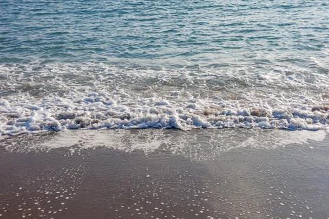 Wave washing over dark sandy shore Stock Photos