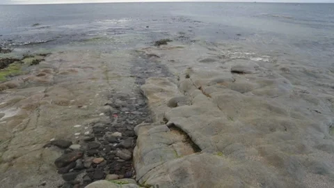 Wave worn pebbles in a rock crevice and tides. Northumberland. UK. Stock Footage 266486256