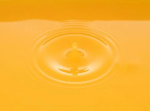 The waves after a few drops of orange juice. Stock Photos