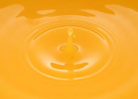 The waves after a few drops of orange juice. Stock Photos