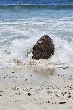 Waves against large rocks on the beach shore Stock Photos