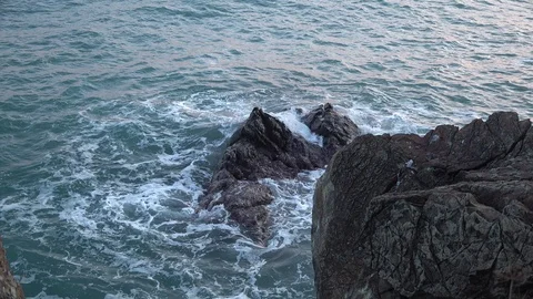 WAVES AGAINST ROCKS AT SUNSET IN WINTER IN LIGURIA Stockbeeldmateriaal 100887269