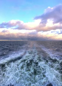 Waves and clouds over the ocean at sunset with a view from a boat during an.. 스톡 사진