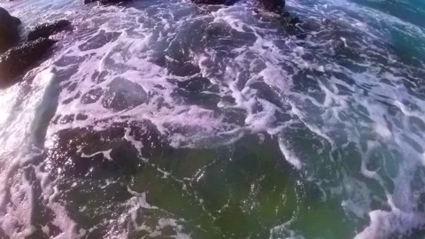 Waves and foam between rocks on the beach 動画素材 244328452