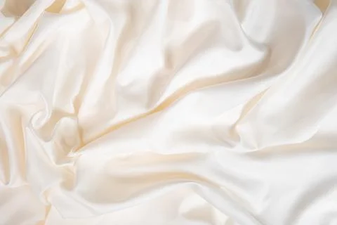 Waves and patterns of crumpled natural satin white milk color fabric. Stock Photos