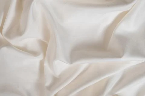 Waves and patterns of crumpled natural satin white milk color fabric. Stock Photos