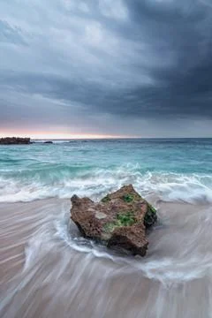 Waves and rocks on the beach with cloudy overcast sky Stock-Fotos