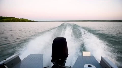 Waves and splashes from a motor boat while riding on a lake at sunset Stock Footage