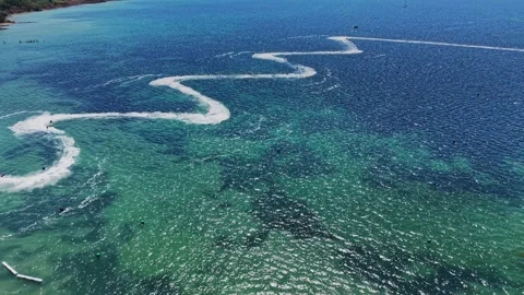 Waves and watercraft create patterns on the ocean surface near a beach Stock Footage 339652986
