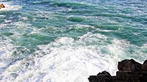 Waves and white water crashing on rocks with silhouette of rocks in foreground 库存影片 80281110