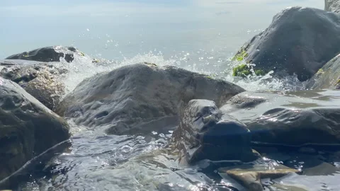 The waves are beating against the rocks lying on the shore. Stock Footage 156803532