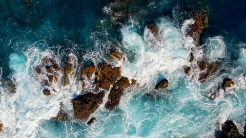 Waves are breaking on stones. Wave foaming and splashing ocean surf. Aerial top Stock-Footage 124016642