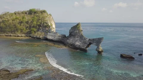 Waves are coming through the rock toward the cost aerial footage of Indonesia Stock Footage 101984740