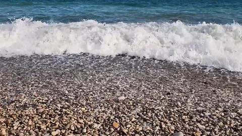 Waves are crashing dramatically onto the beautiful Pebble Beach, creating an Stock Photos