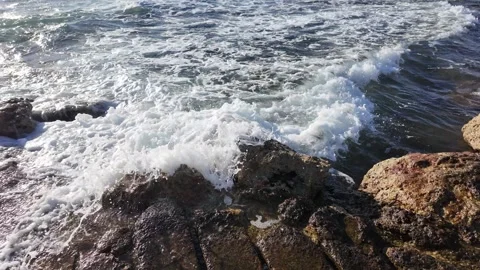Waves are crashing energetically against the rugged rocky shoreline during Stock Footage 319834593