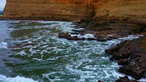 Waves are gently  bounching off the rocks of a small rock sea defence Stock Footage 230204488
