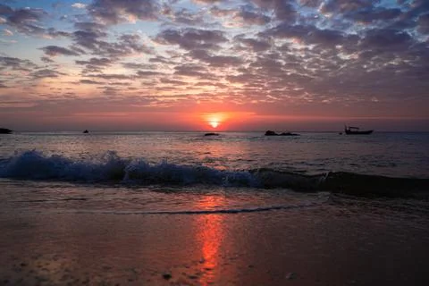 Waves arriving at the beach during a sunset Stock Photos