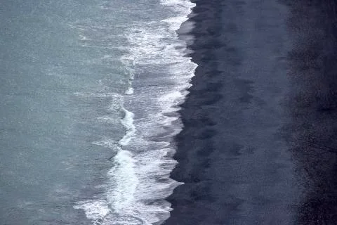 Waves of the Atlantic ocean fall on the black sand of the beach of Iceland fr Stock Photos