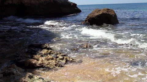 Waves from the Atlantic Ocean roll across rocks at the water's edge Stock Footage 65206645