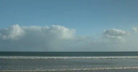 Waves onto Beach in Cornwall, England with cloudy blue sky Stock Footage 125489669
