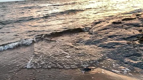 Waves on the beach hitting rocks in sunset in slow motion Stock Footage