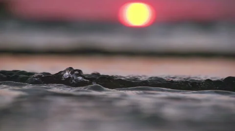 Waves on the beach with setting orange sun and red sky Stock Footage 64228869