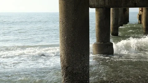 Waves beat against the pillars of a concrete pier. Stock Footage 128799237