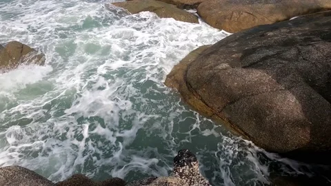 The waves beat against the rocks and create a white foam. Stock Footage 230079176