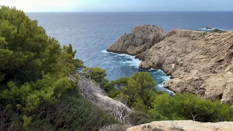 Waves beat against rocks in a bay in Mallorca Видео 114707439
