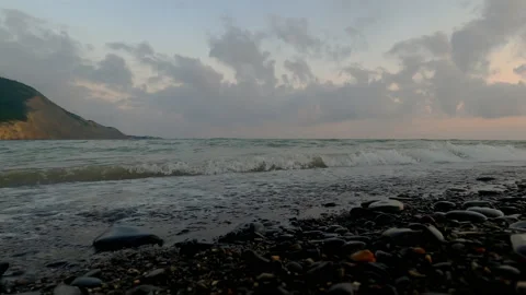 Waves beat against the shore, scattering small stones to the sides. Stock Footage 156803254
