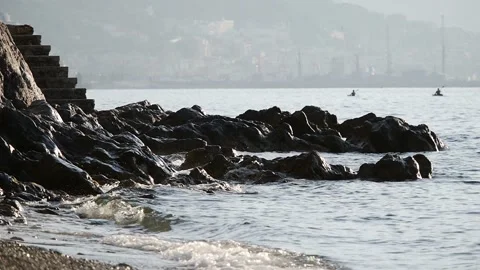 Waves beat on the rocks. Two koyaks are floating in the rear. Stock Footage 99833791