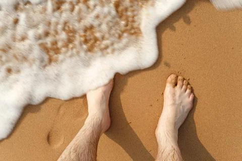 Waves beating against legs on the beach Stock Photos