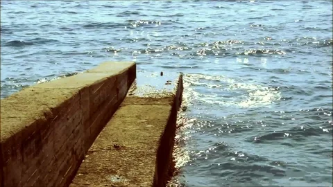 Waves beating against a pier Stock Footage 77863099