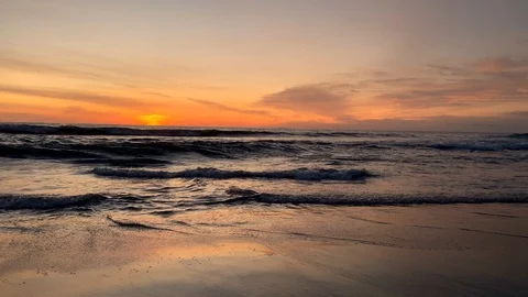 Waves in beautiful beach under orange sunset light Stock Footage 125842903