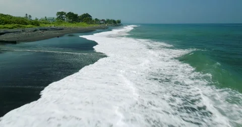 Waves on black sand beach in Bali. Slow motion. Drone view Video stock 246614076