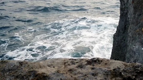 Waves in the blue sea hitting the rocks in slow motion Stock Footage 130294564