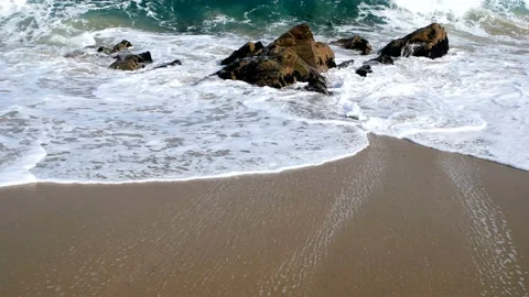 The waves of blue strike the rocks and produce white bubbles. Stock Footage 145968025