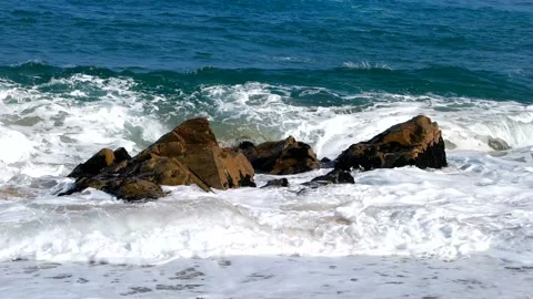 The waves of blue strike the rocks and produce white bubbles. Stock Footage 145968085