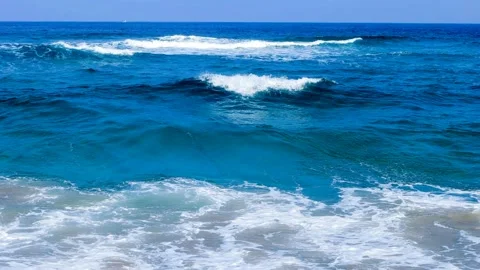 The waves of blue strike the rocks and produce white bubbles. Stock Footage 145968122