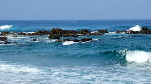 The waves of blue strike the rocks and produce white bubbles. Stock Footage 145968279
