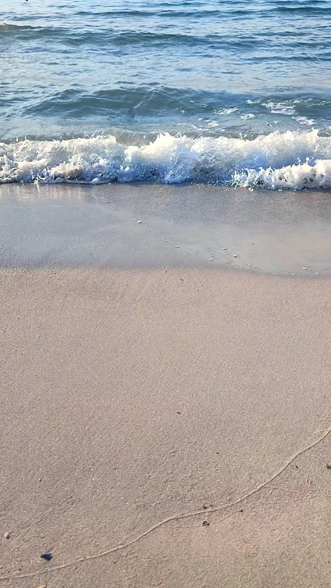 Waves blue transparent water rolling onto the sand of a sandy beach Vertical Stock Footage 324985229
