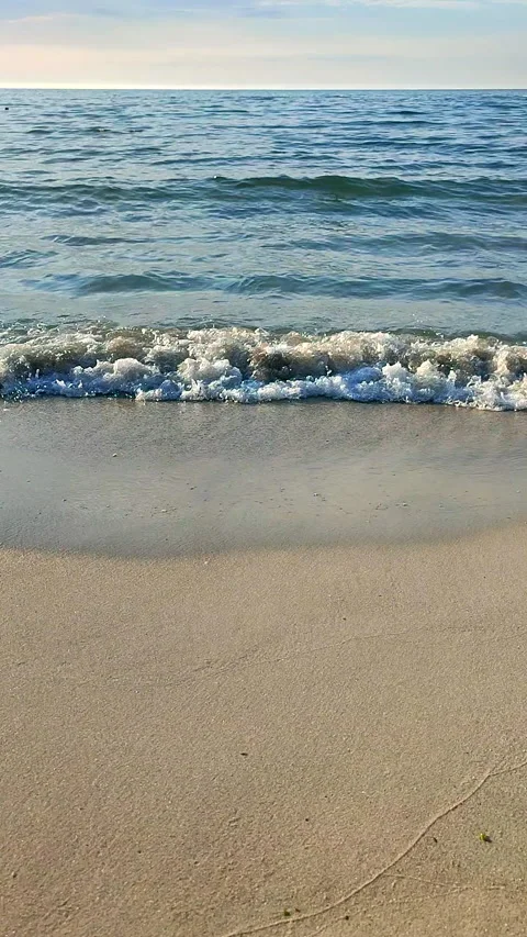 Waves blue transparent water rolling onto the sand of a sandy beach Vertical Stock Footage 324985232