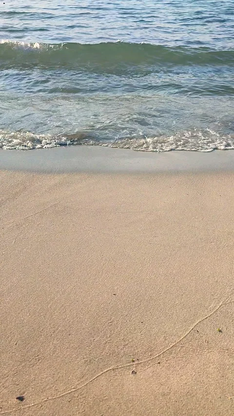 Waves blue transparent water rolling onto the sand of a sandy beach Vertical Stock Footage 326380488