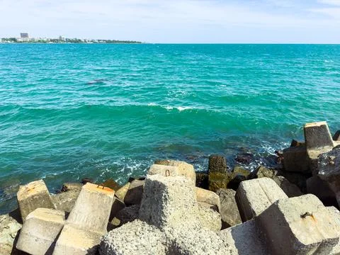 Waves break against concrete blocks near the shoreline in a coastal area du.. Stock Photos
