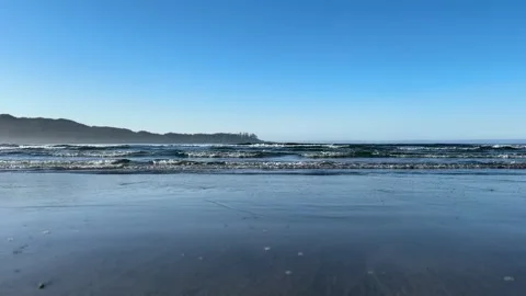 Waves break against a sandy beach with larger waves crashing in the background. Stock Footage 238862223