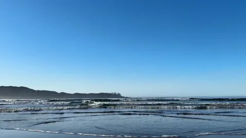 Waves break against a sandy beach with larger waves crashing in the background. Stock Footage 238863526