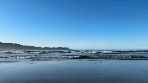 Waves break against a sandy beach with larger waves crashing in the background. Stock Footage 238863548