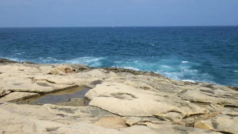 Waves break along an open horizon rocky valletta shoreline tide pools pooling Stock Footage 341800836