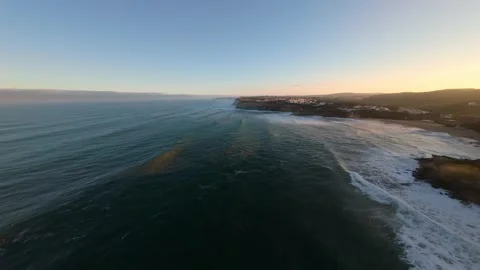 Waves break along rocky shore under bright sun; Ericeira Видео 346371212