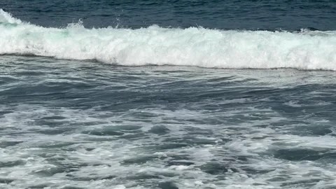Waves break and retreat back into the sea, creating layered motion across blue 動画素材 329745718